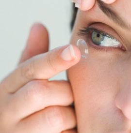 A woman placing a contact lense on to her eye